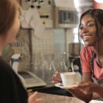 A coffee shop employees talks to a customer