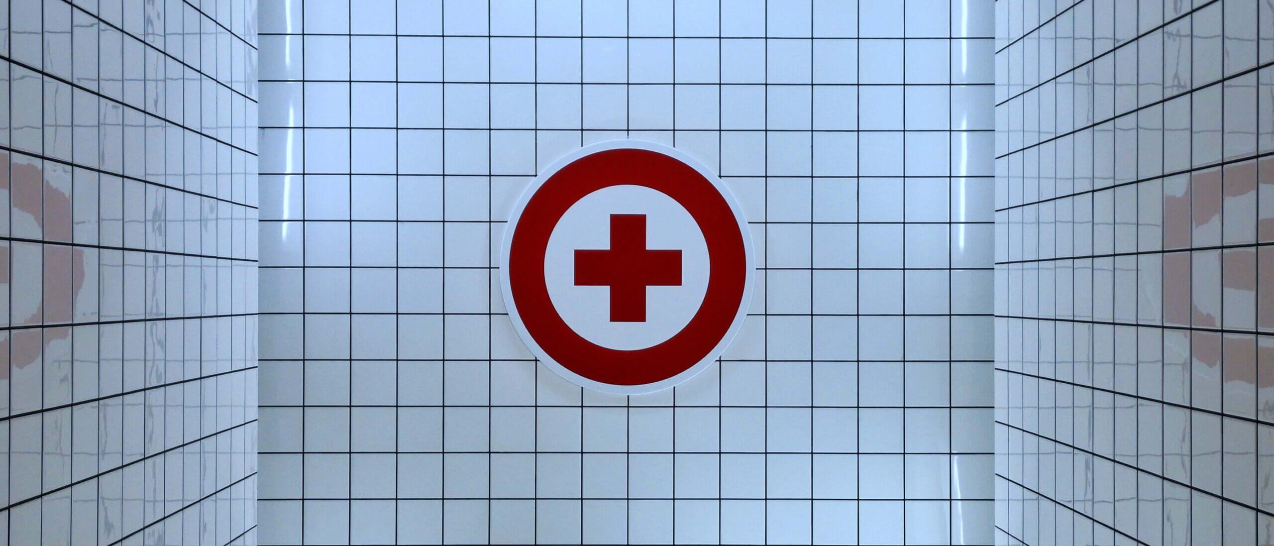 Red medical cross symbol on white tile