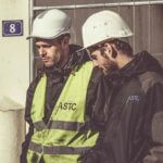 Employees wearing hardhats while surveying project