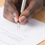 Person signing document with pen