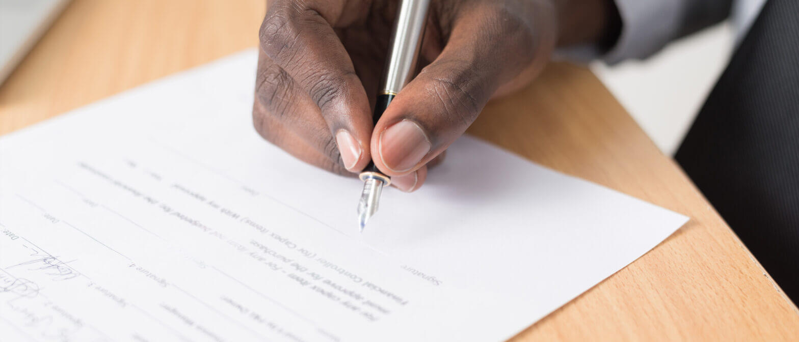Person signing document with pen