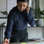 Woman standing at desk while on the phone