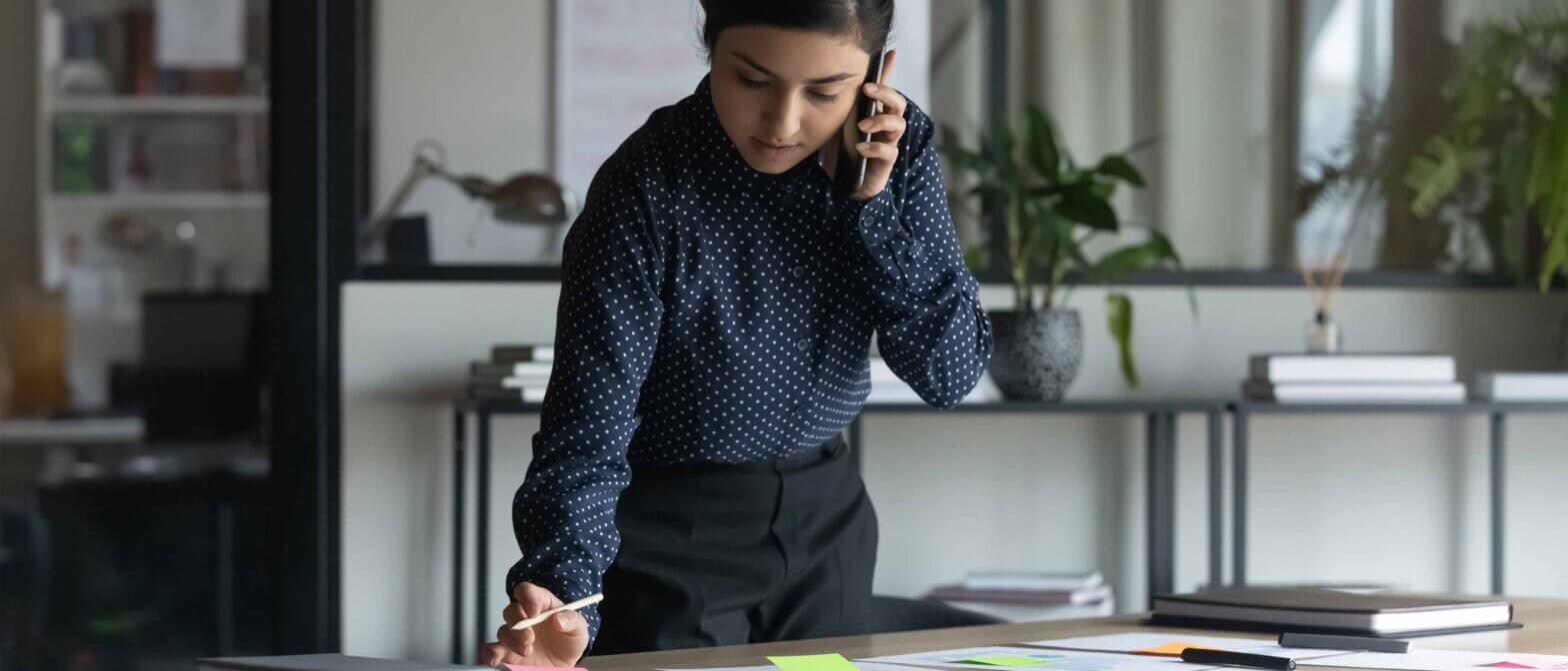 Woman standing at desk while on the phone