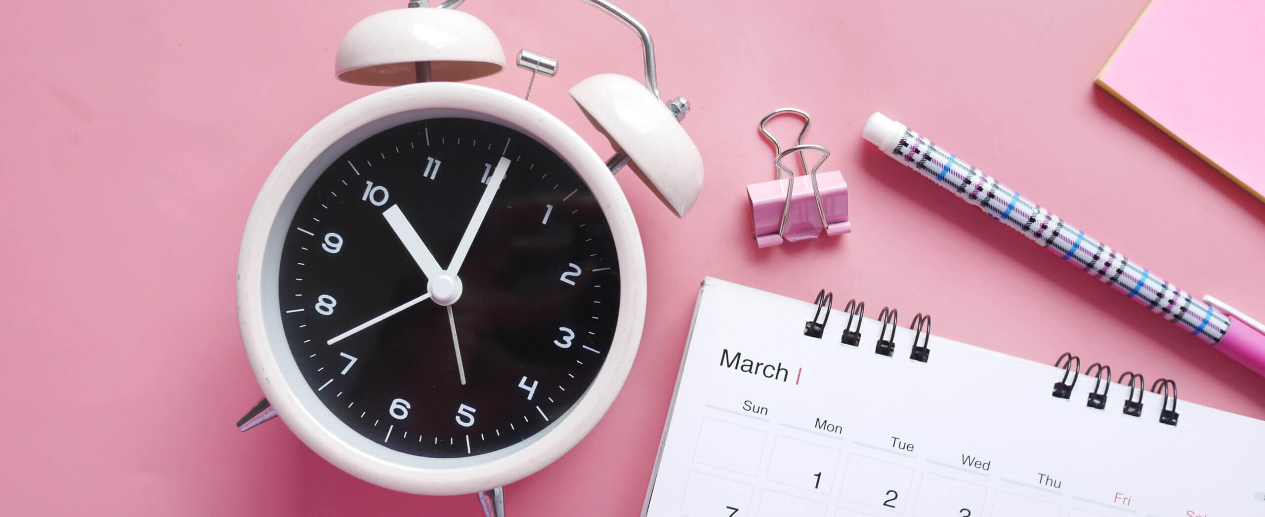 Image of a clock and a calendar with pink background
