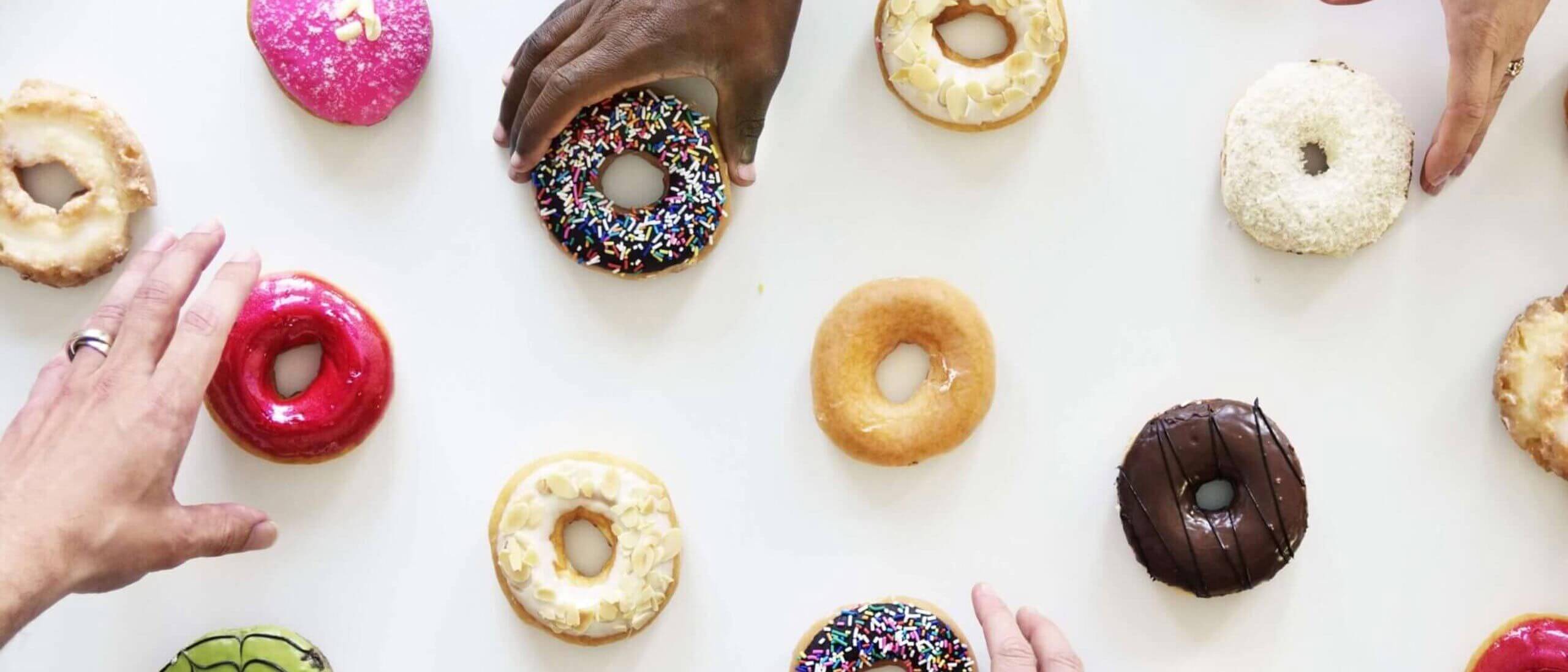 Diverse group of people grabbing donuts off a table